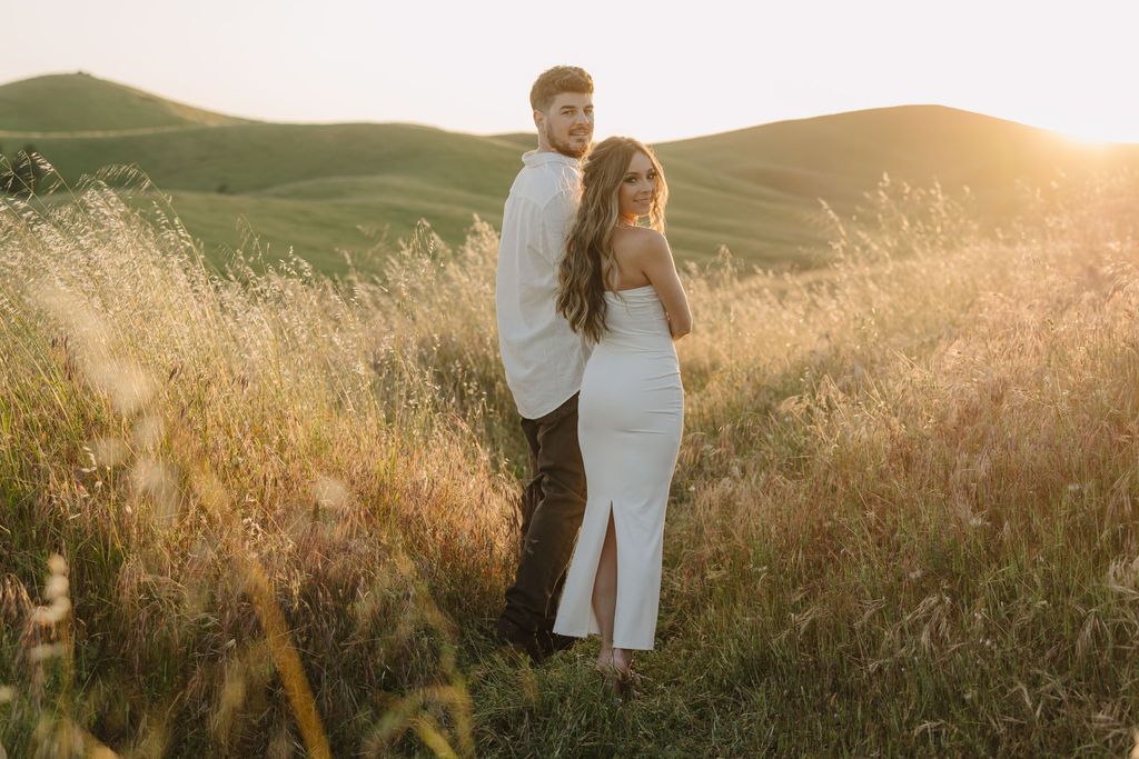 A couple looking back as they walk in a field.