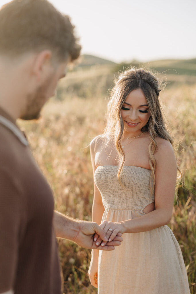 A man holding a woman's hand showing off an engagement ring. 